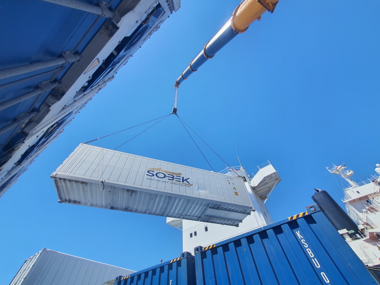 Sobek container suspended from a crane above the ship deck