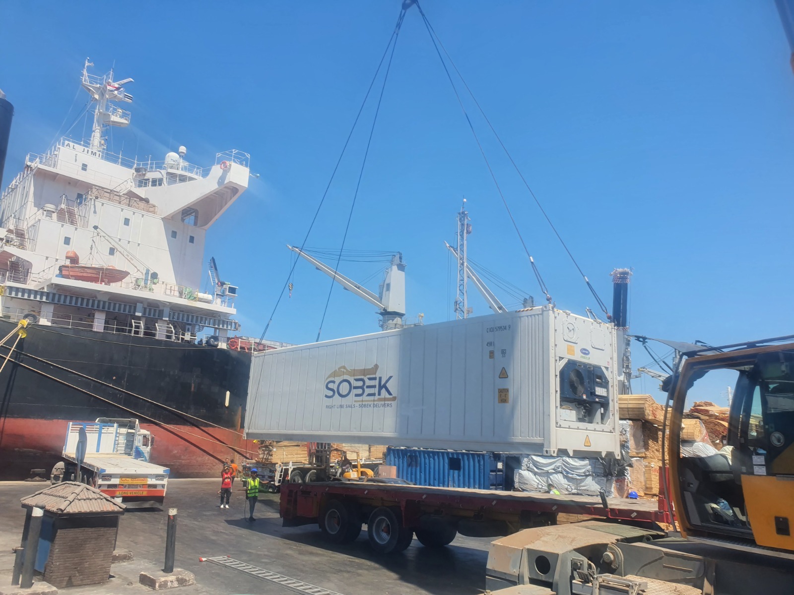 Reefer container suspended over a trailer beside a ship